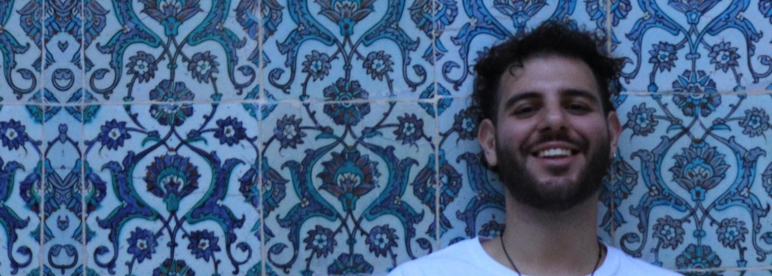 Manuel Scionti, smiling in front of a blue-tiled wall